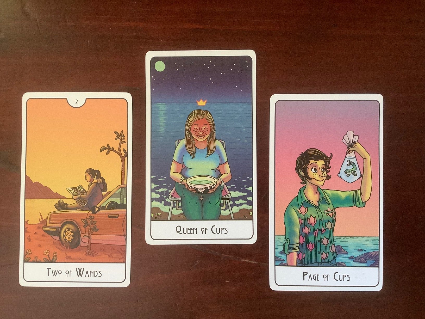 3 tarot cards against a dark wood background