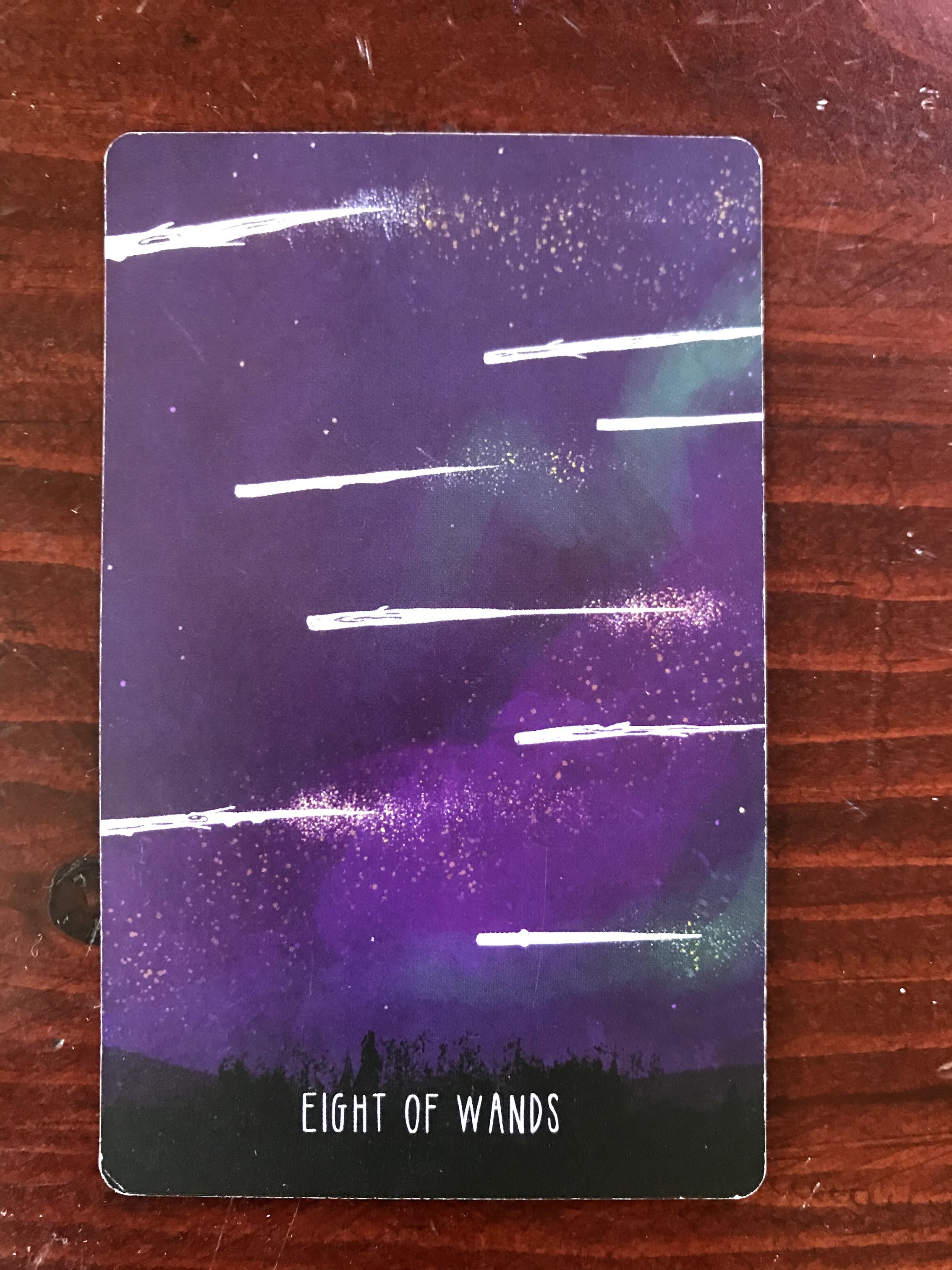 a tarot card depicting 8 white wands streaking across a purple sky