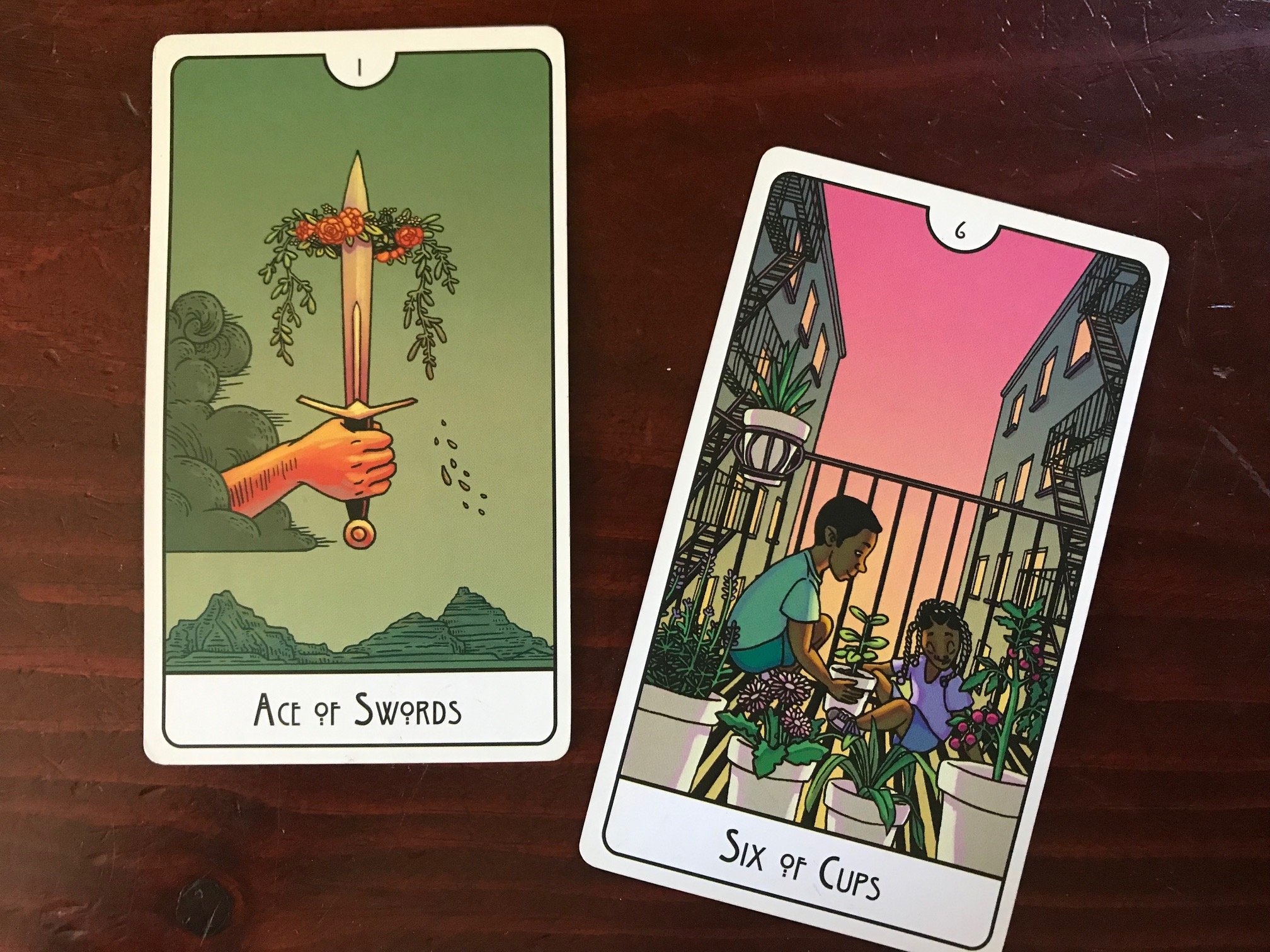 two tarot cards against a dark wood background