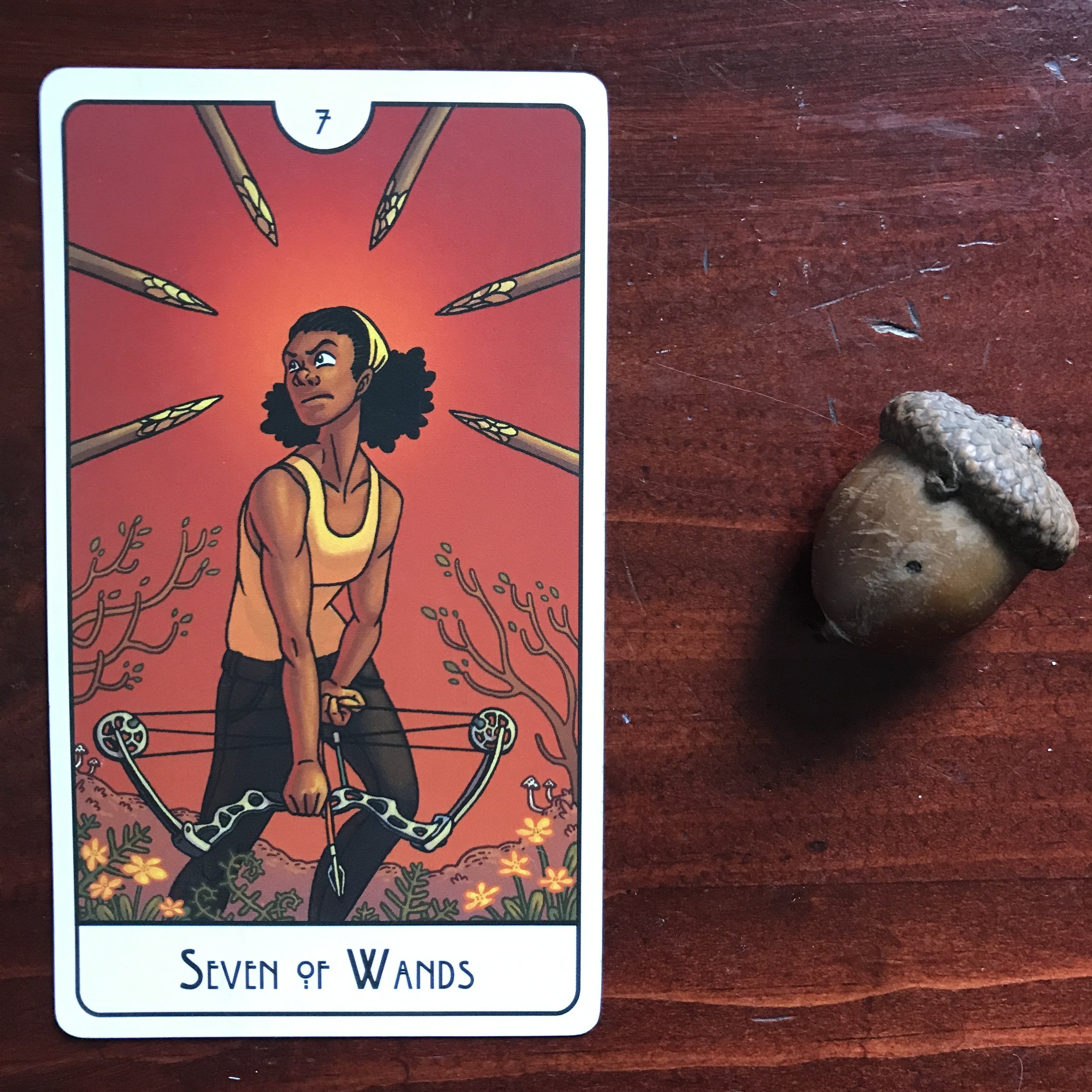 a tarot card and an acorn against a dark wood background