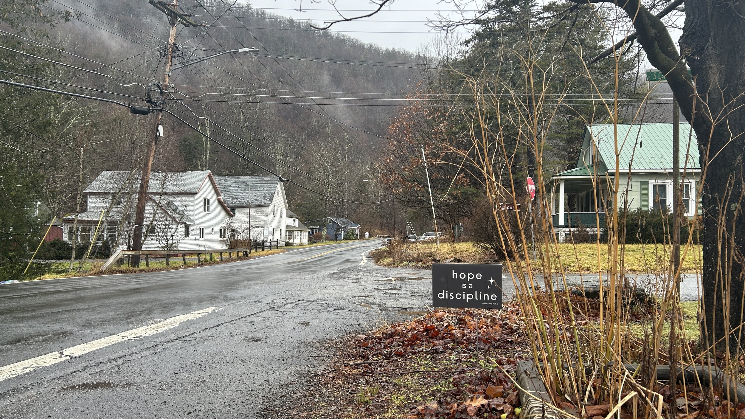 early winter country road with houses and a sign that says hope is a discipline