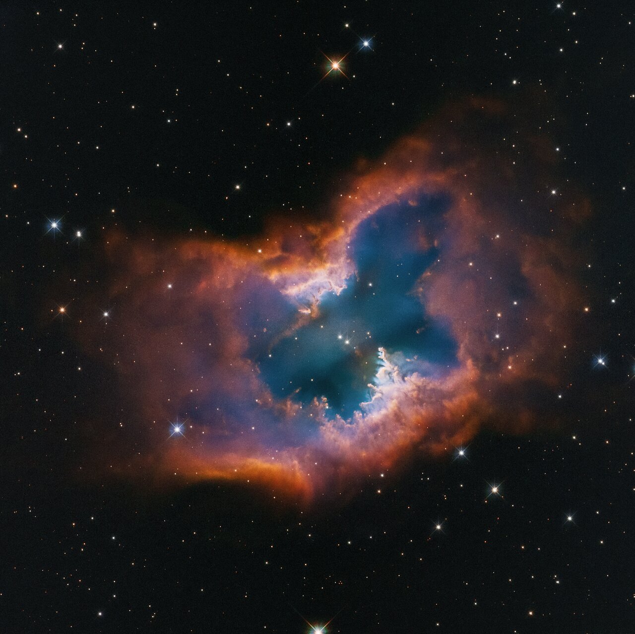 a blue butterfly-shaped central nebula ringed in pinkish orange against a black starry space sky