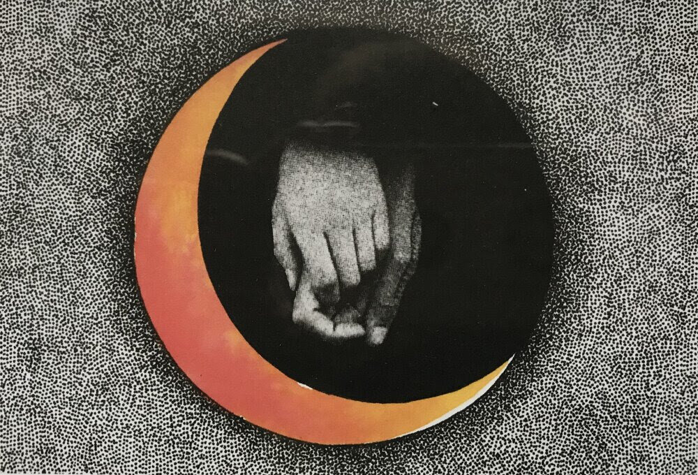 an image of two black and white hands holding each other in a black circle framed by an orange crescent moon with a dotted black and white background
