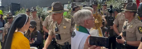 on the left, a nun wearing a black habit and yellow t-shirt listens to a tall man wearing the hat and uniform of a state trooper, on the right, a white man with white hair and glasses wearing liturgical vestments holds a gold monstrance in front of state troopers