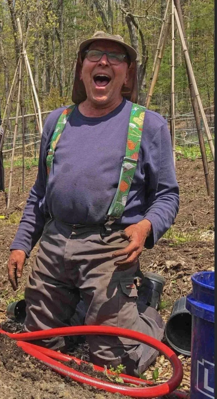 a white guy in his 70s with a little potbelly hanging over his pants, wearing green suspenders, with garden-dirty hands and a mouth wide open in joy
