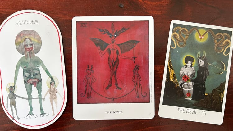 3 devil tarot cards against a wood background