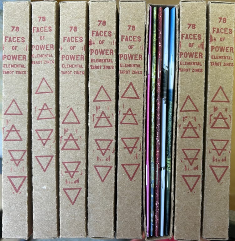 red-stamped cardboard spines of a zine box set lined up next to each other, one box set is turned around to show stapled spines of individual zines