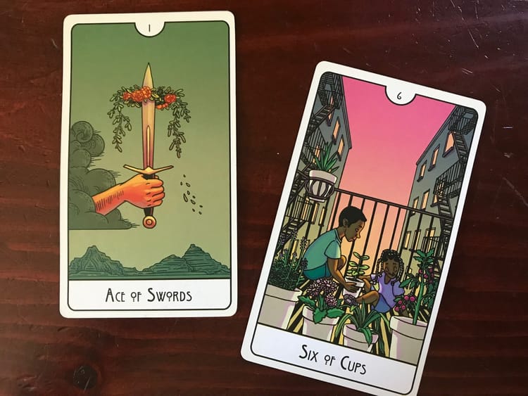 two tarot cards against a dark wood background