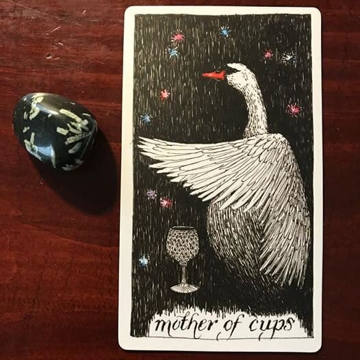 a line drawing of a white swan in profile with wing outstretched over a faceted goblet against a starry black background