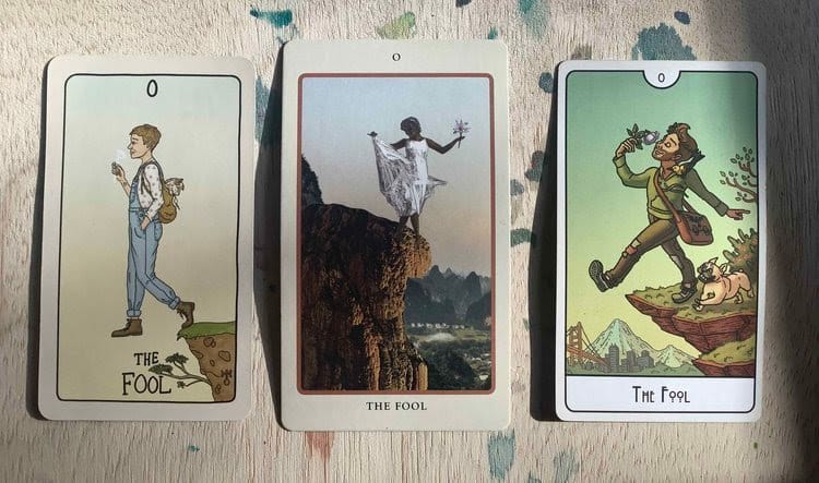 three tarot cards on a paint-splattered wood background