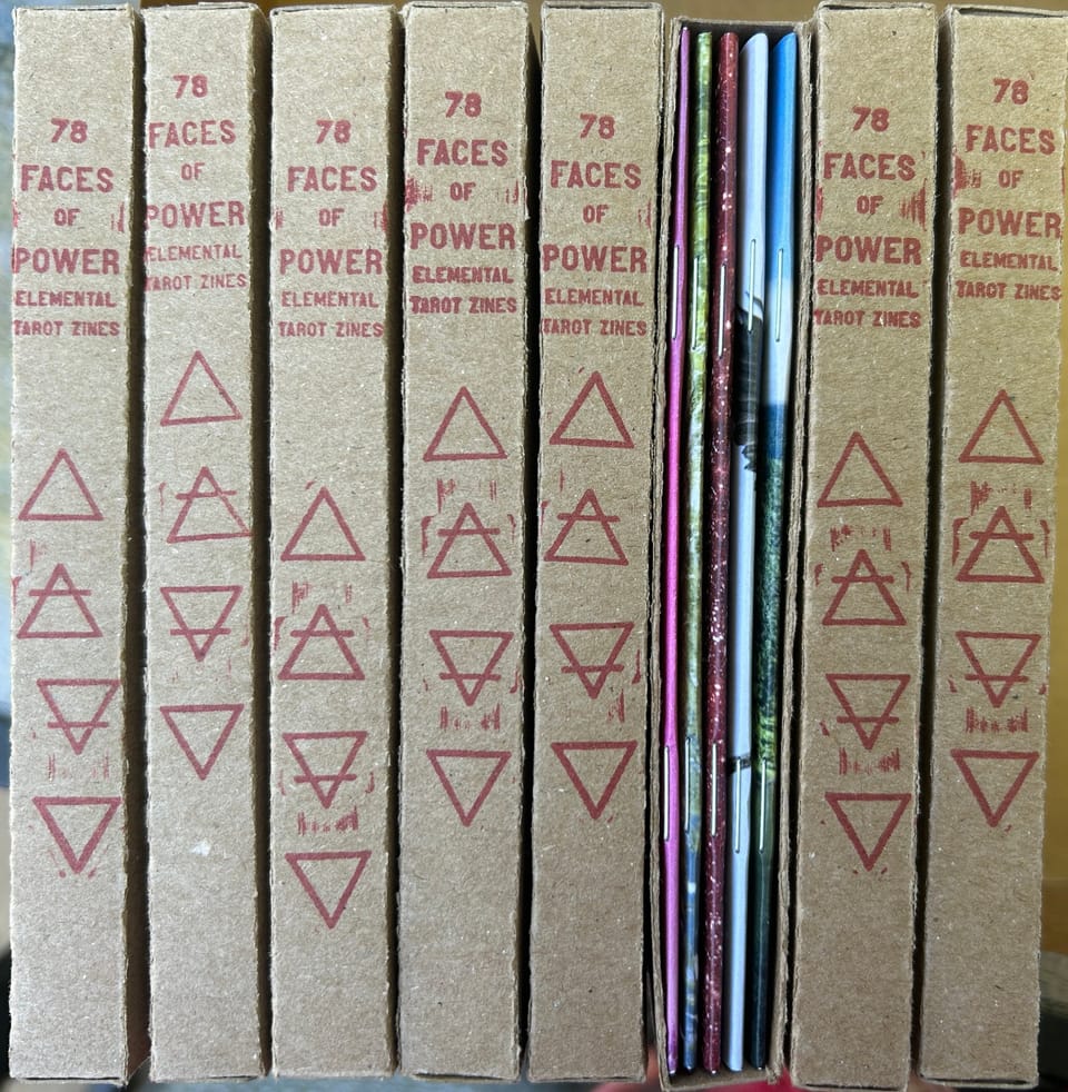 red-stamped cardboard spines of a zine box set lined up next to each other, one box set is turned around to show stapled spines of individual zines