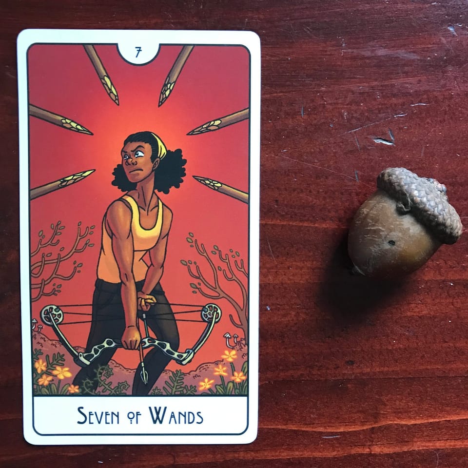 a tarot card and an acorn against a dark wood background