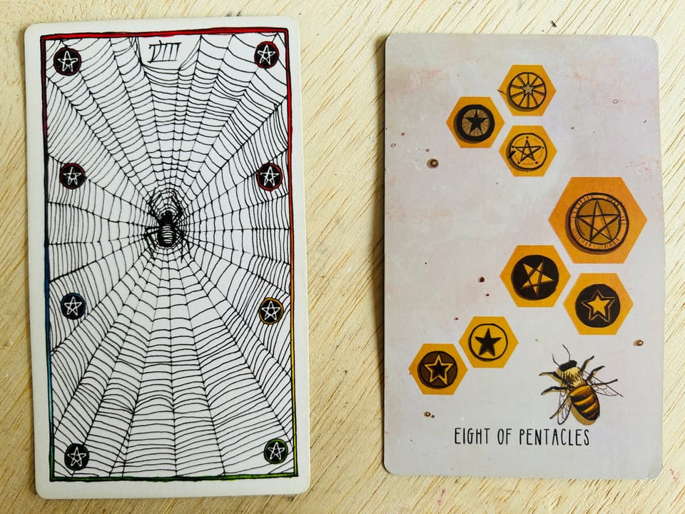 two tarot cards on a light wood surface with diagonal grain